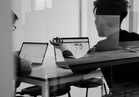 Two people working on laptops in conference room